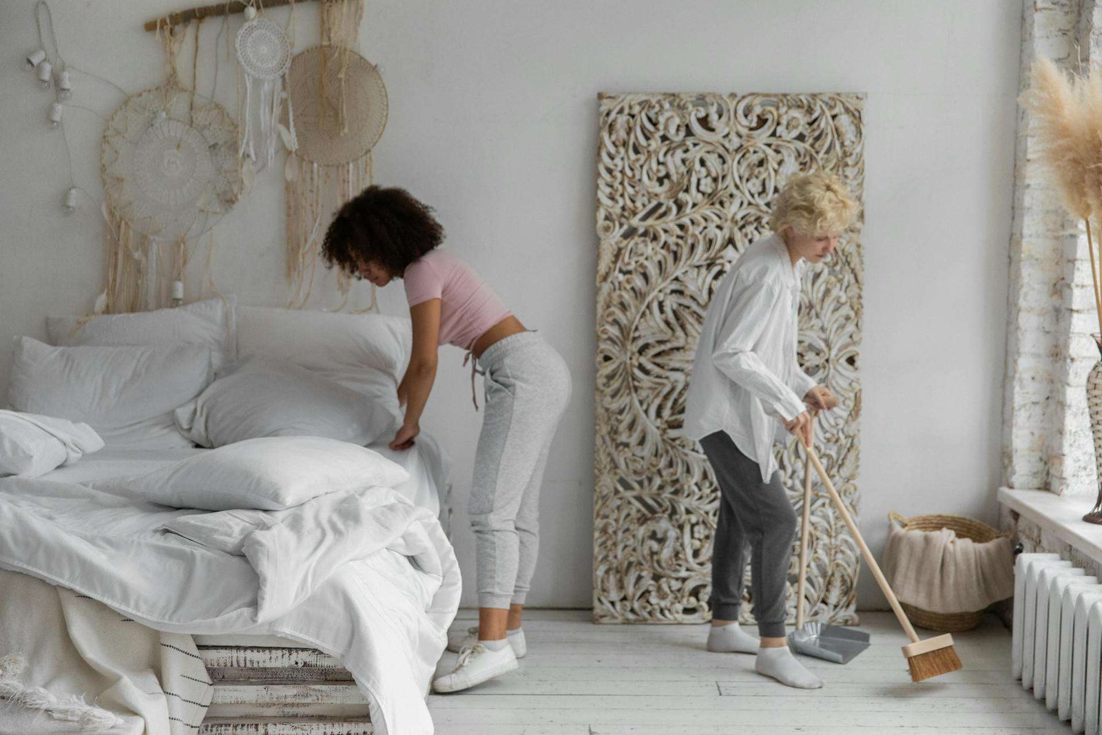 GURU® employee cleaning the top of a nightstand in a white bedroom