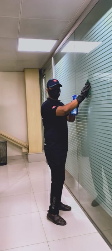 Guru Cleaning Experts team member cleaning a glass window