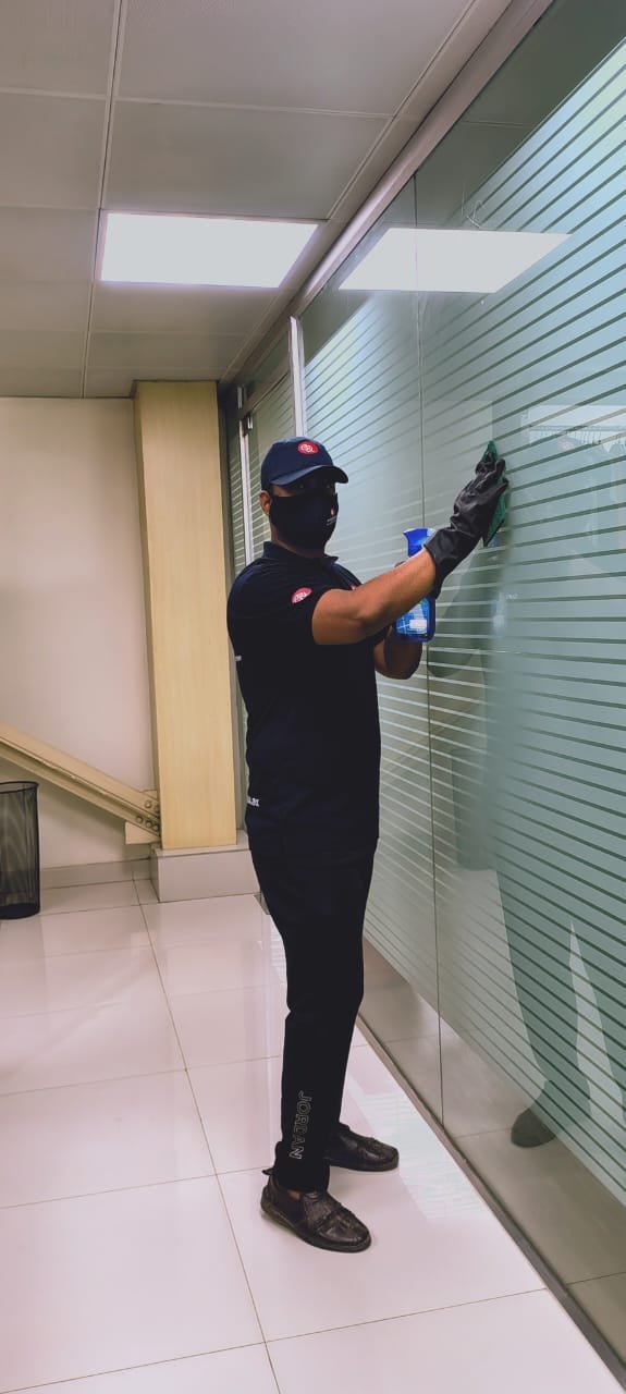 Guru Cleaning Experts team member cleaning a glass window