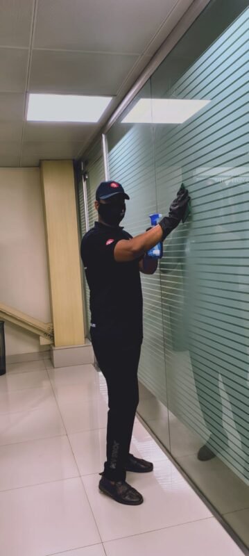 Guru Cleaning Experts team member cleaning a glass window