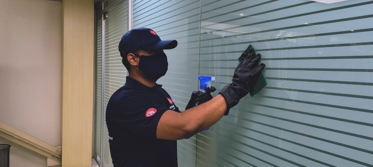 Guru Cleaning Experts team member cleaning a glass window