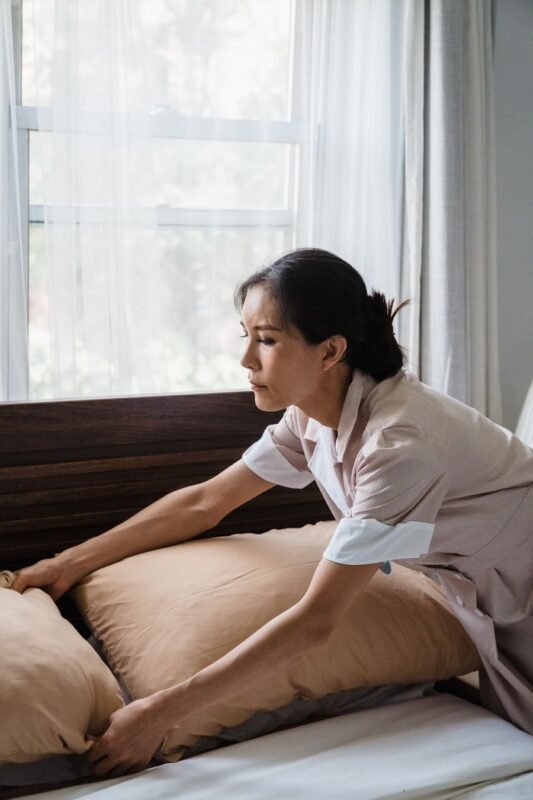Housekeeper arranging a mattress and pillows
