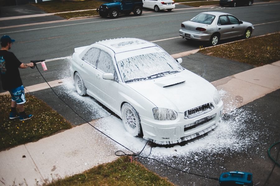 Pressure washing a car on a driveway